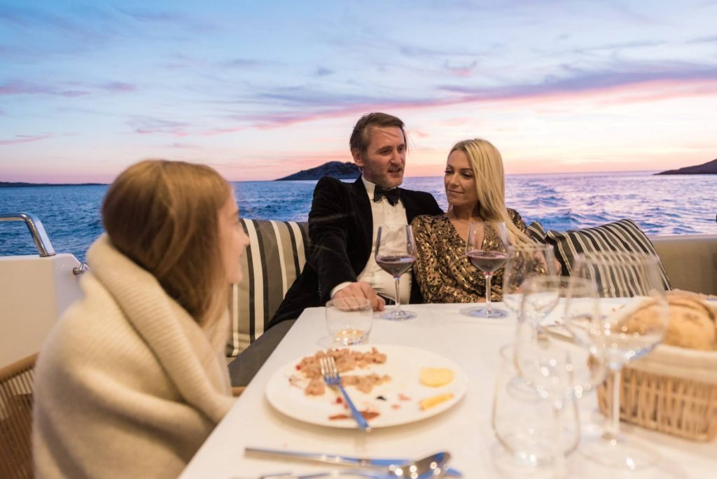 couple with a daughter having a dinner on a main yacht deck