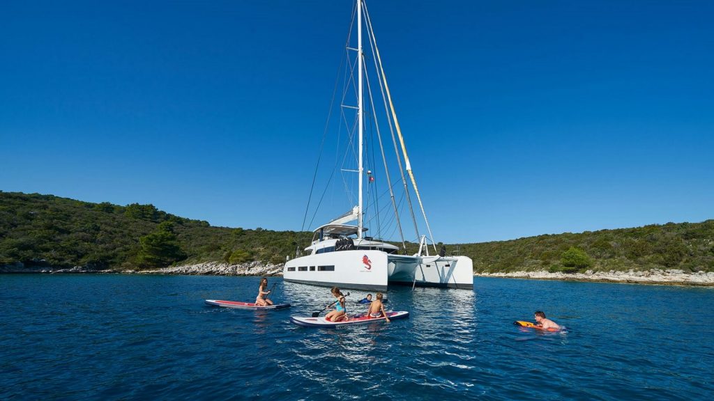 guests are swimming in the sea by an anchored adriatic dragon catamaran yacht