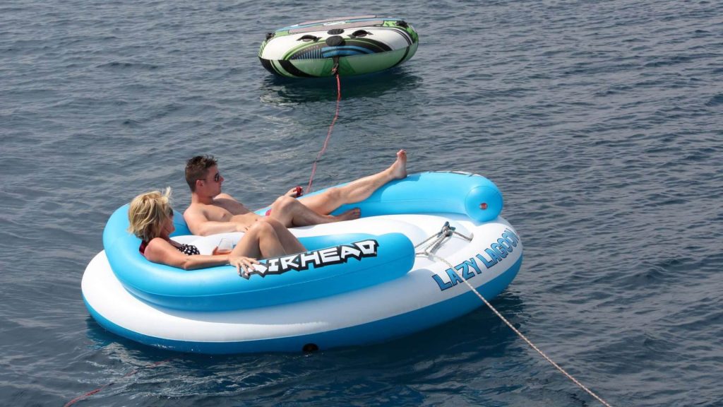 couple in a sea sunbathing on a rubber boat