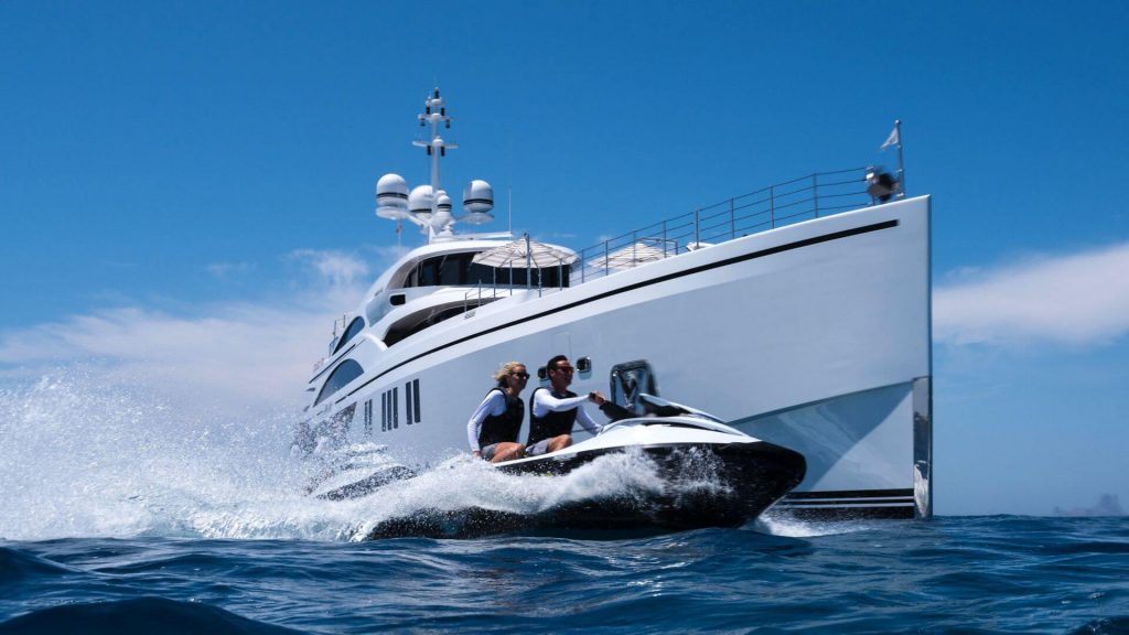 couple on a jet ski having fun by a anchored superyacht
