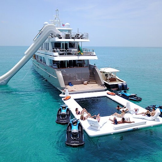 A yacht with a stern-side waterpark and floating pontoon, with adjacent water toys 
