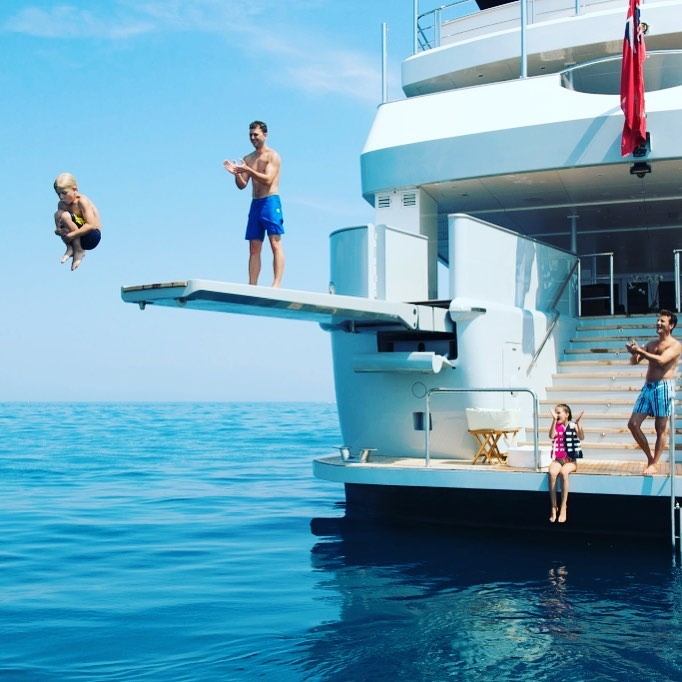 The kid is jumping from a family yacht charter into the sea