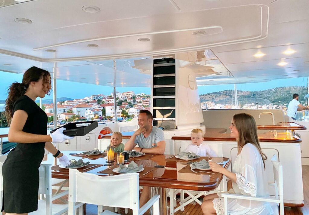 family served by a crew member on board a yacht