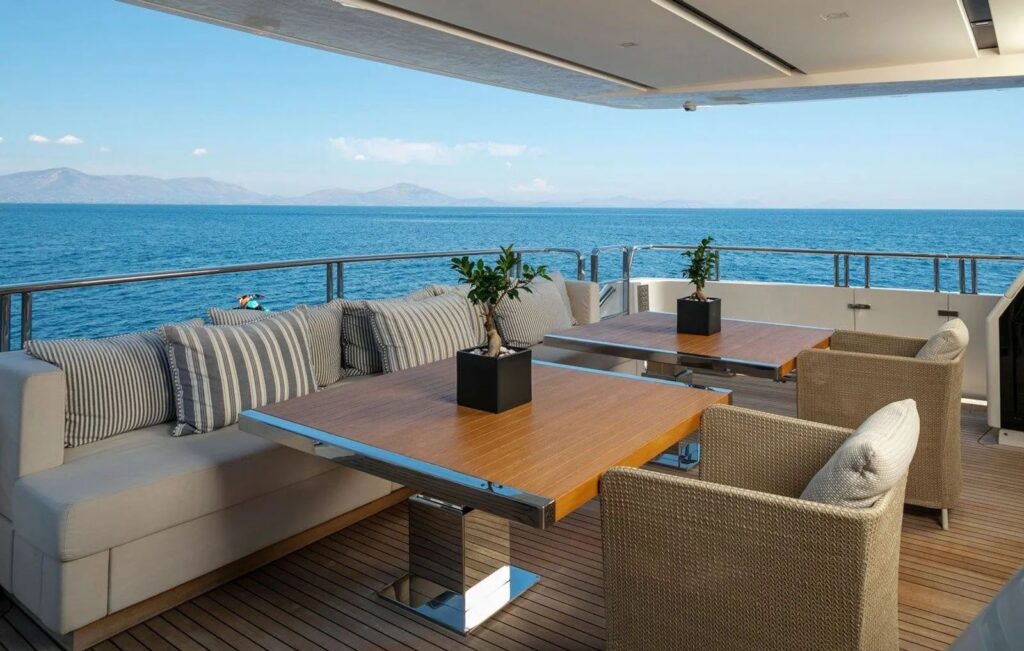 2 dining tables on the yacht aft deck with a sofa & chairs
