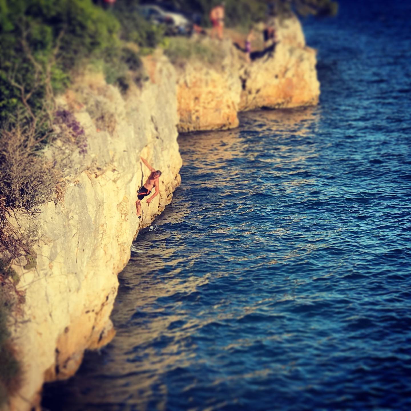 A rock climber trying to ascend a short rock above the sea