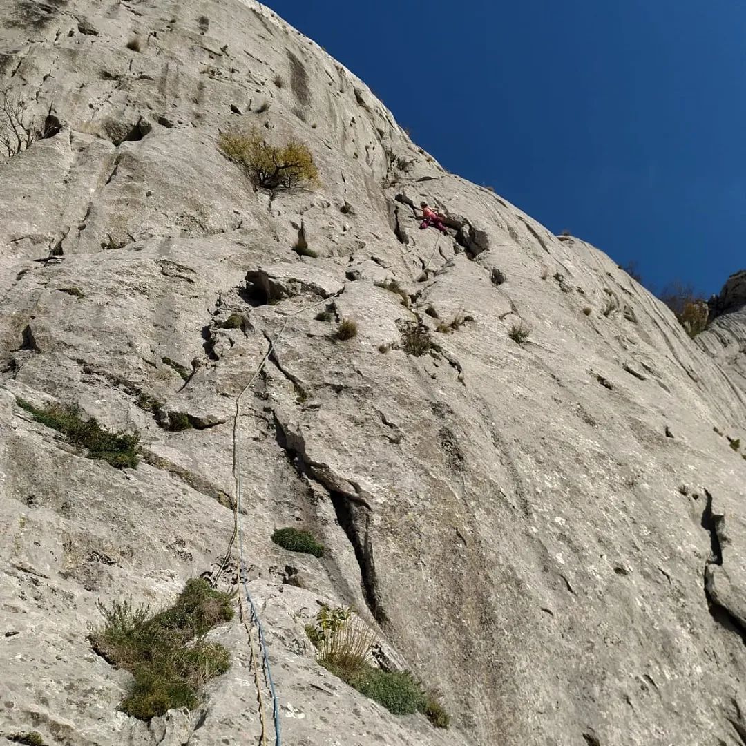 Climber slowly edging alongside a steep and high rock