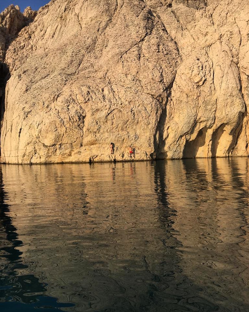 A rock climbing beginning the ascent near the water`s edge